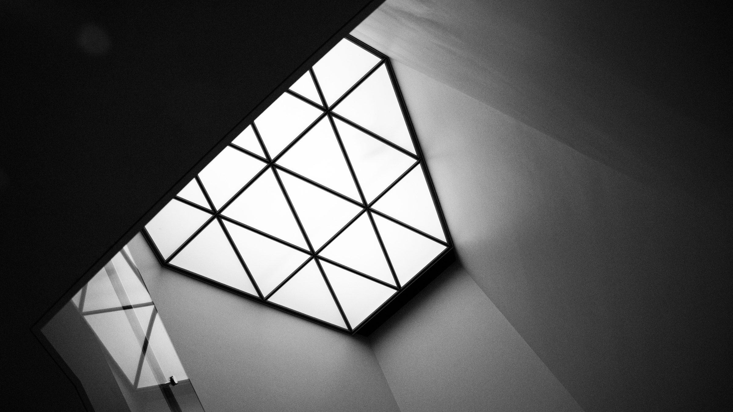 A triangulated glass skylight set into a dark angular ceiling, lit from above.