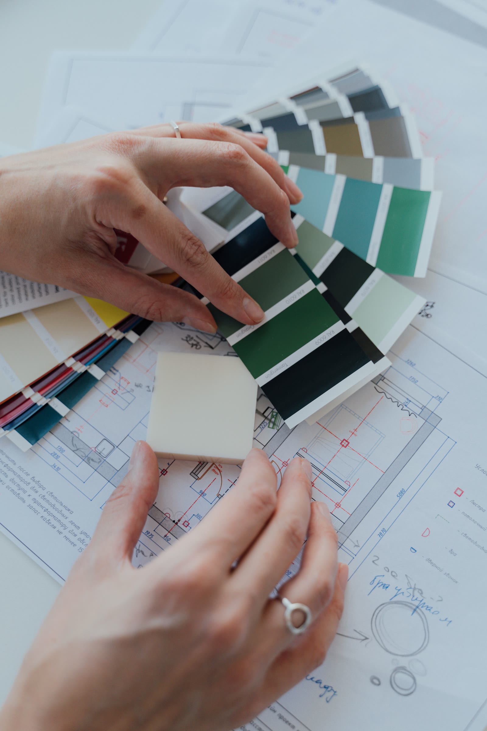 Hands considering colour swatches and plans as part of a design process.